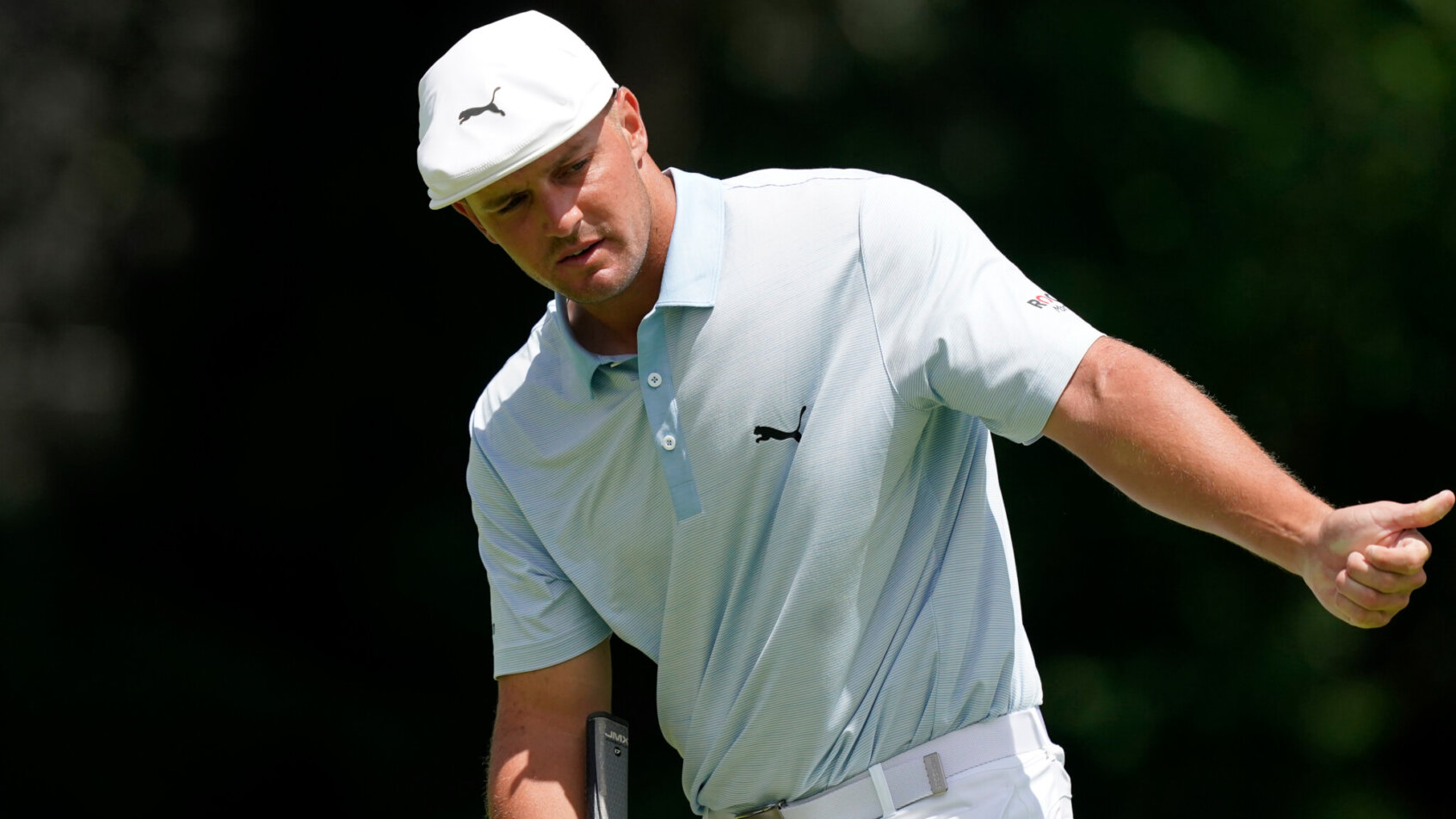 Bryson DeChambeau motions for his putt to move